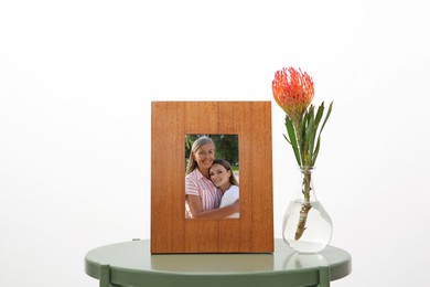 Family portrait of mother and daughter in photo frame on table against white background