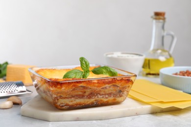 Photo of Tasty cooked lasagna in baking dish on light table