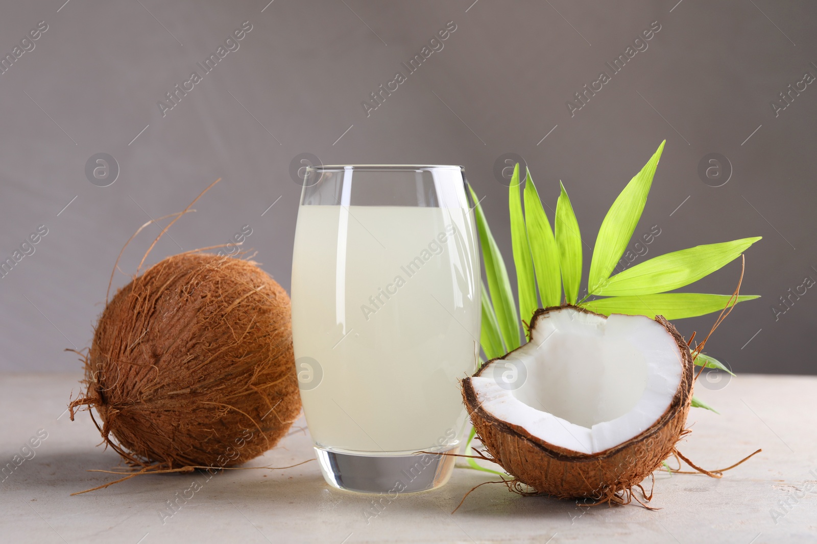 Photo of Glass of coconut water, palm leaves and nuts on light table