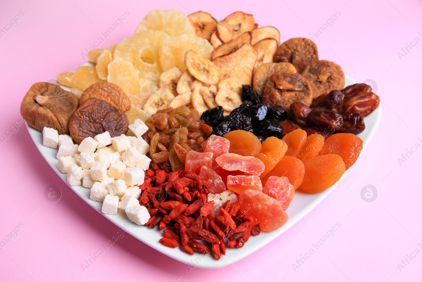 Photo of Plate with different dried fruits on violet background, closeup