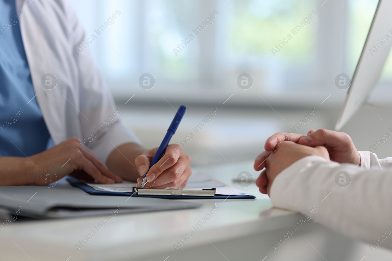 Photo of Professional doctor working with patient at white table in hospital, closeup