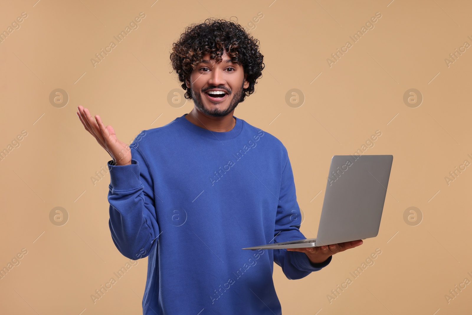 Photo of Smiling man with laptop on beige background