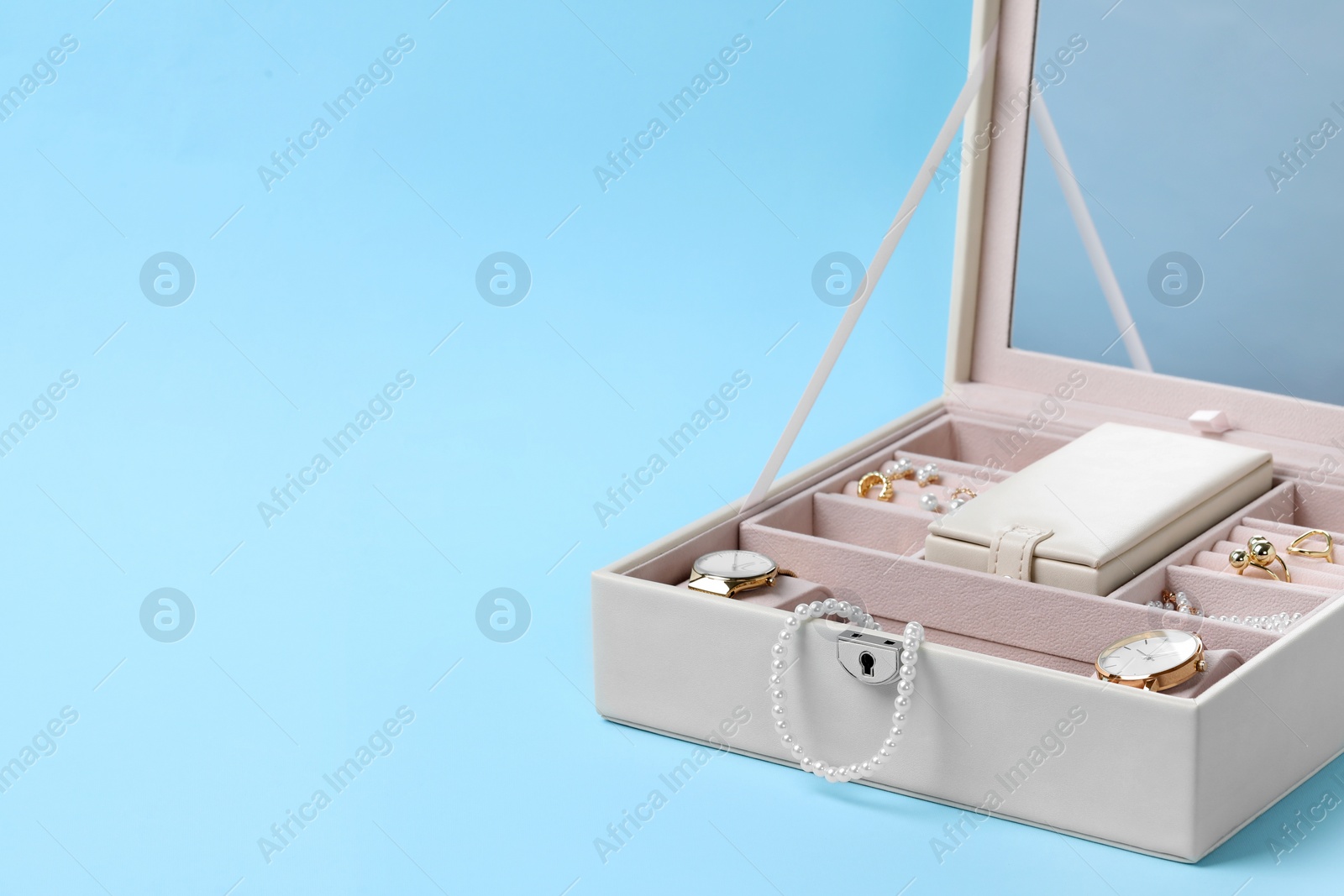 Photo of Jewelry box with many different accessories on light blue background, space for text