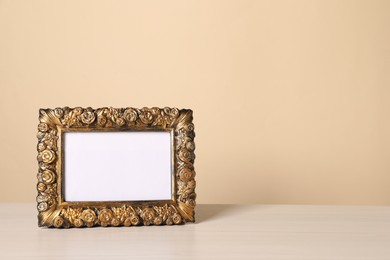 Beautiful vintage empty frame on white wooden table, space for text