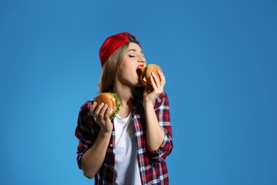 Pretty woman with tasty burgers on color background. Space for text