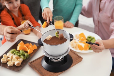 Photo of Family having fondue dinner at table, closeup