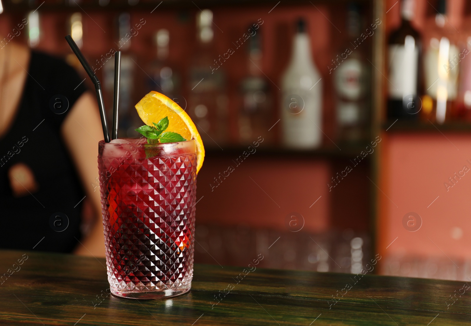 Photo of Glass of delicious cocktail with ice on table in bar