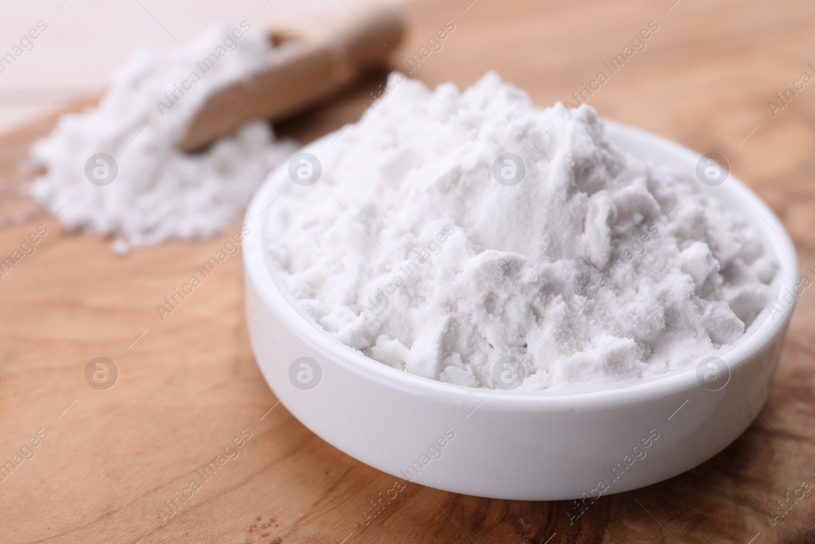 Photo of Starch in bowl on wooden board, closeup view