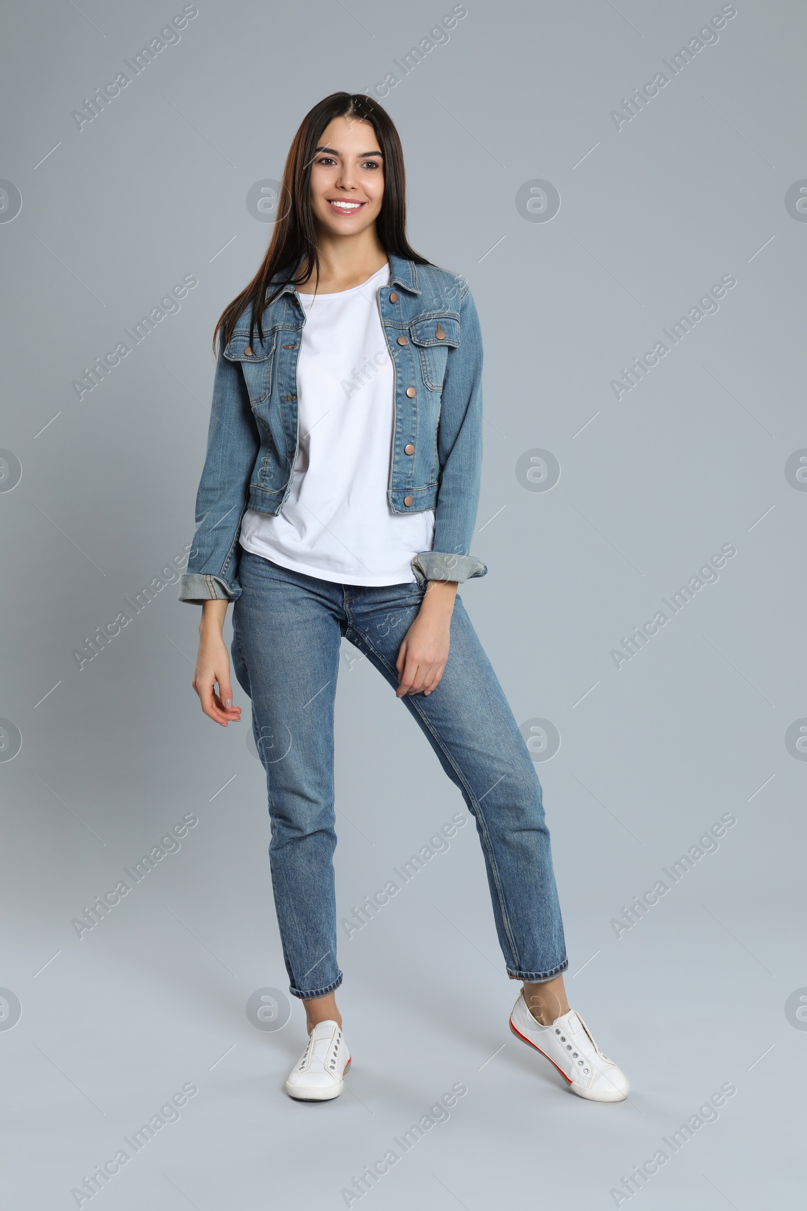 Photo of Young woman in stylish jeans on grey background