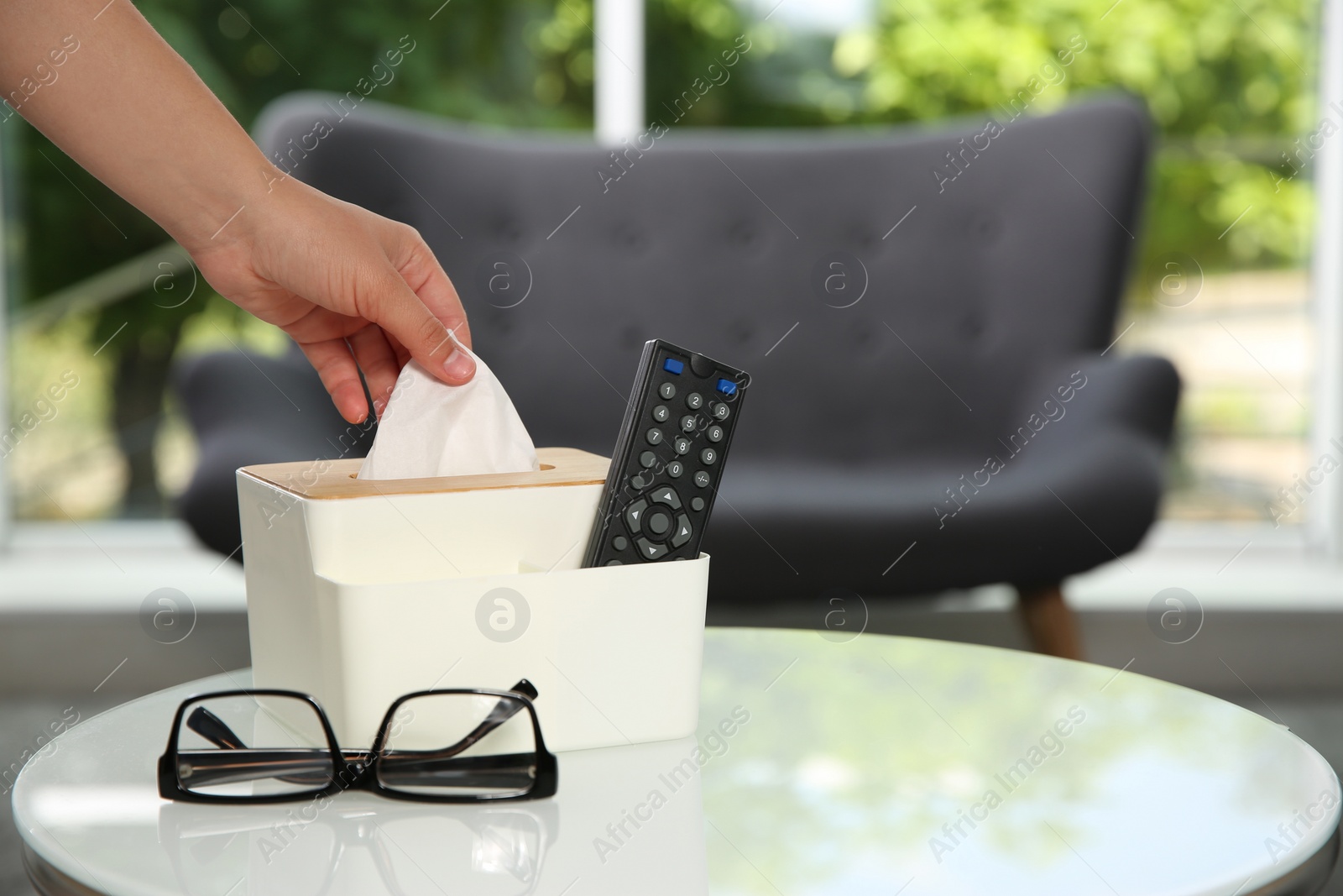 Photo of Woman taking paper tissue out of box on white table at home, closeup. Space for text