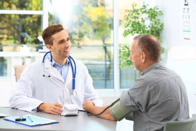 Doctor measuring blood pressure of mature patient in hospital