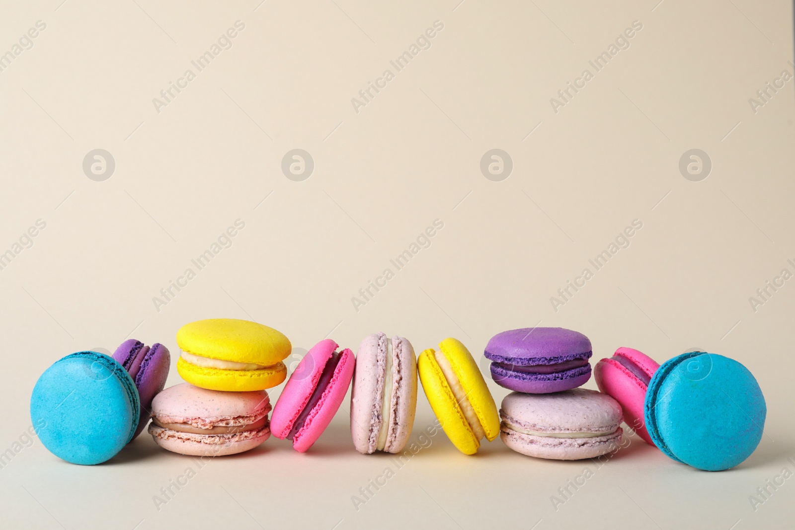 Photo of Delicious colorful macarons on beige background. Space for text