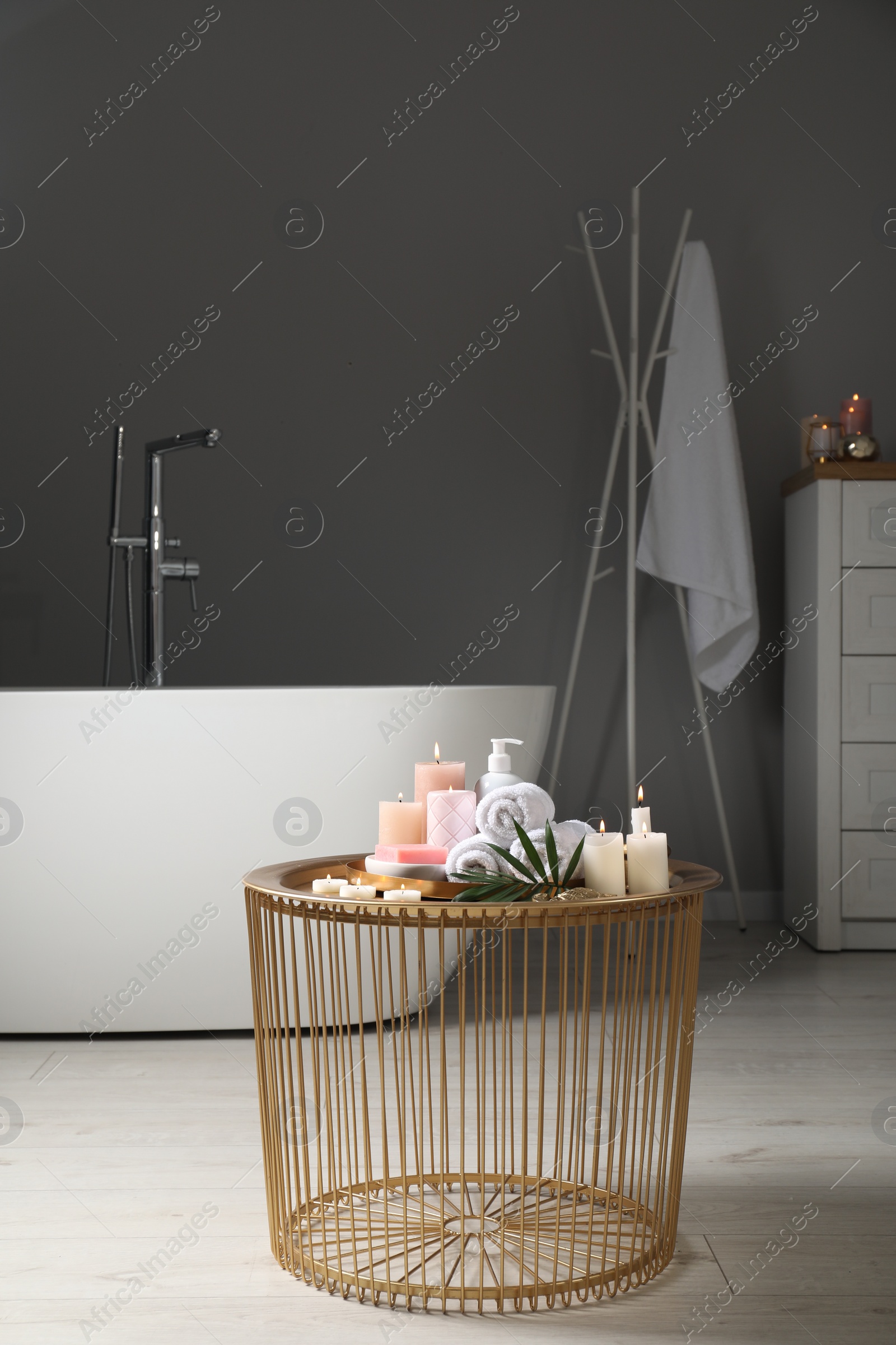 Photo of Stylish bathroom interior with ceramic tub and spa products on table