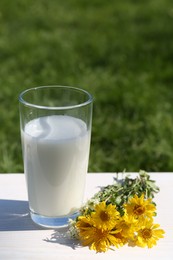 Photo of Glass of fresh milk on white wooden table outdoors