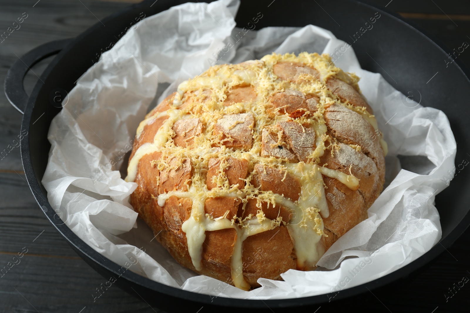 Photo of Freshly baked bread with tofu cheese and lemon zest on black wooden table, closeup