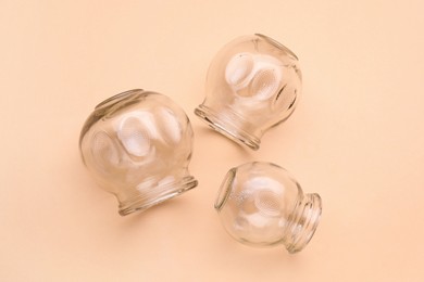 Photo of Glass cups on light coral background, flat lay. Cupping therapy