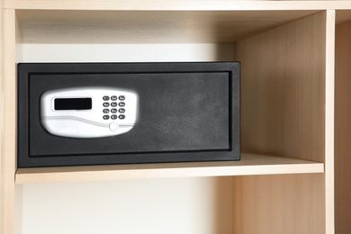 Photo of Black steel safe with electronic lock in wooden closet