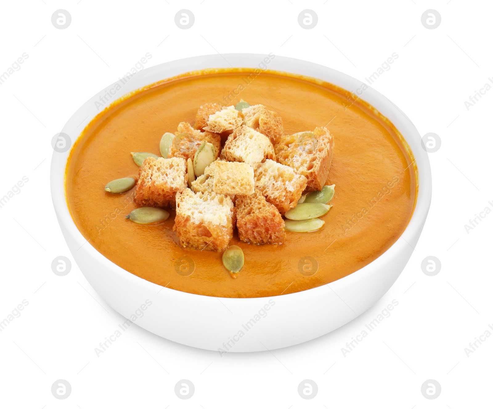 Photo of Delicious pumpkin cream soup with seeds and croutons in bowl isolated on white