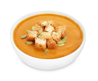 Delicious pumpkin cream soup with seeds and croutons in bowl isolated on white