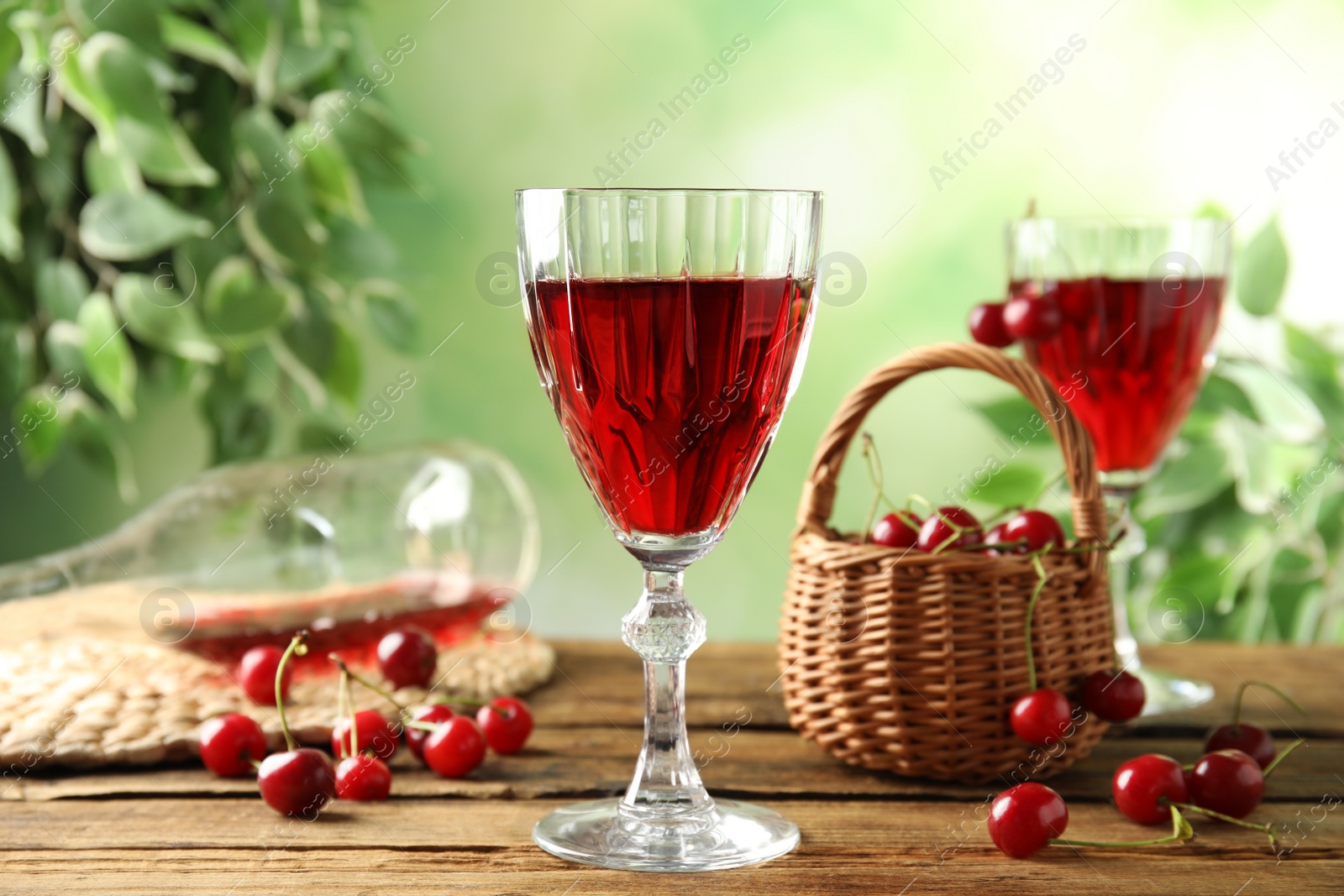 Photo of Delicious cherry wine with ripe juicy berries on wooden table