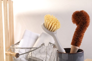 Cleaning brushes in holder and basket with cloth indoors, closeup