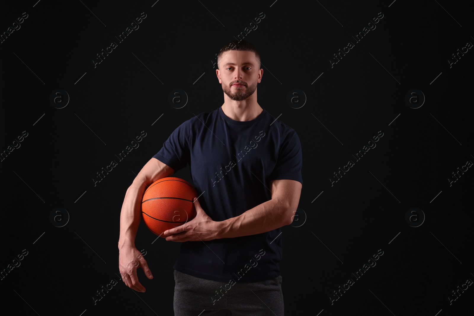 Photo of Athletic young man with basketball ball on black background