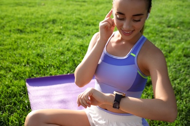 Photo of Woman checking fitness tracker after training in park
