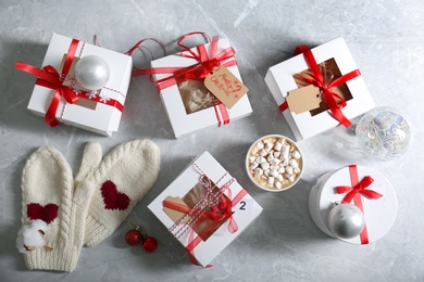 Flat lay composition with Christmas gifts, cup of marshmallow cocoa and festive decor on light grey marble table. Creating Advent calendar