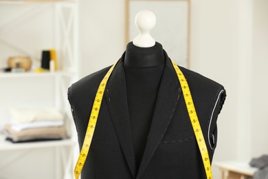 Photo of Mannequin with unfinished jacket and measuring tape in tailor shop