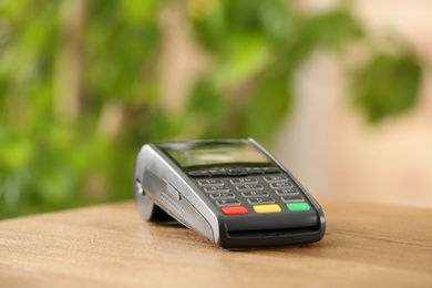 Modern payment terminal on table indoors. Space for text