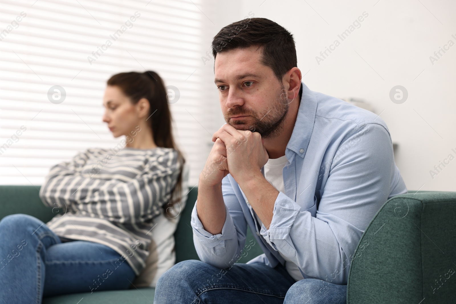 Photo of Offended couple ignoring each other after quarrel indoors, selective focus. Relationship problems