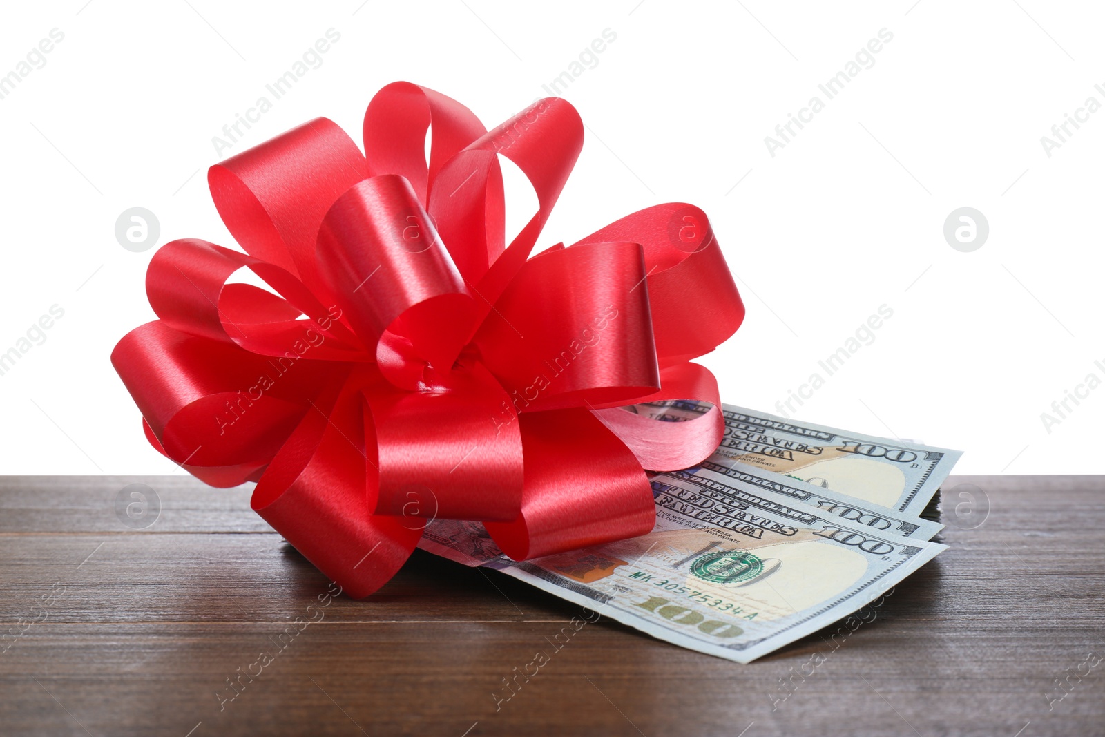 Dollar bills with red bow on wooden table against white background Photo of Dollar bills with red bow on wooden table against white background