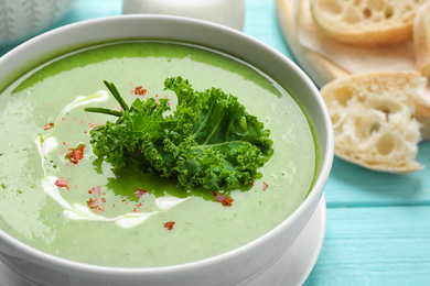 Photo of Tasty kale soup on light blue wooden table, closeup