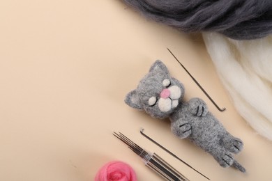 Photo of Felted cat, wool and tools on beige table, flat lay. Space for text