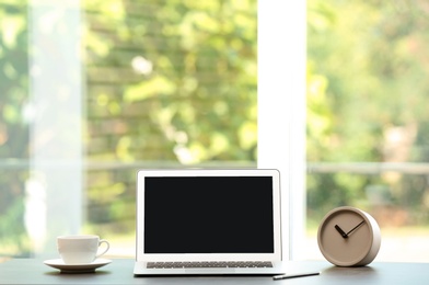 Modern laptop on table against window. Mock up with space for text