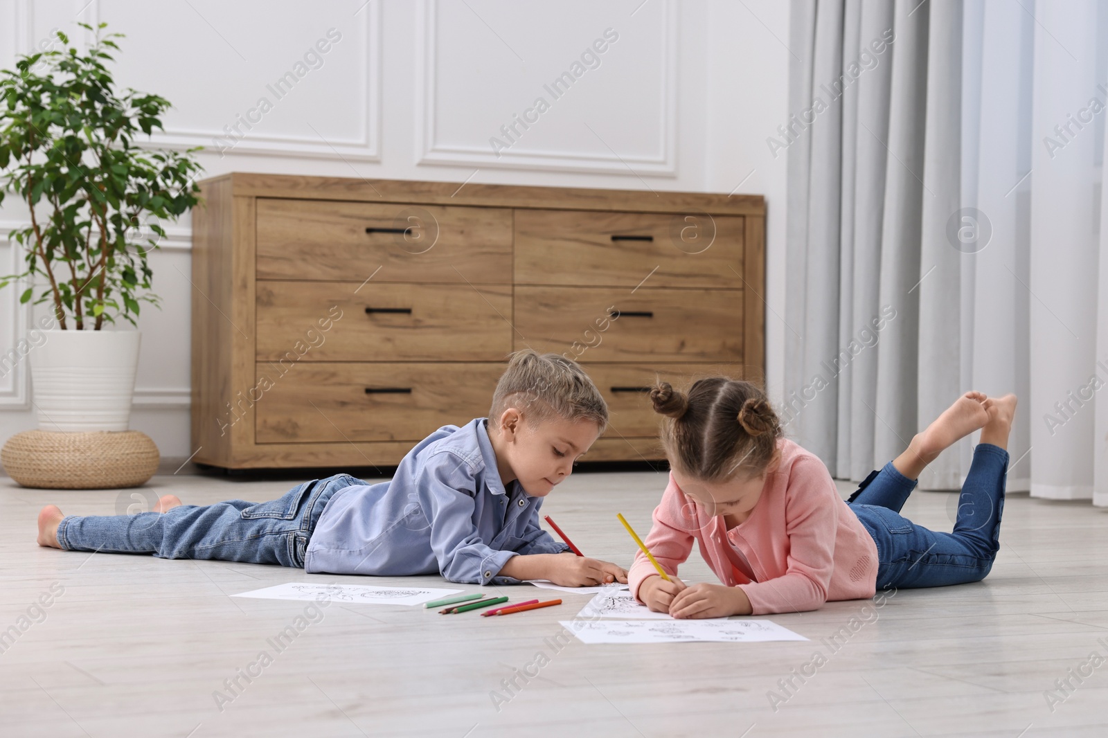 Photo of Cute little children coloring on warm floor at home. Heating system