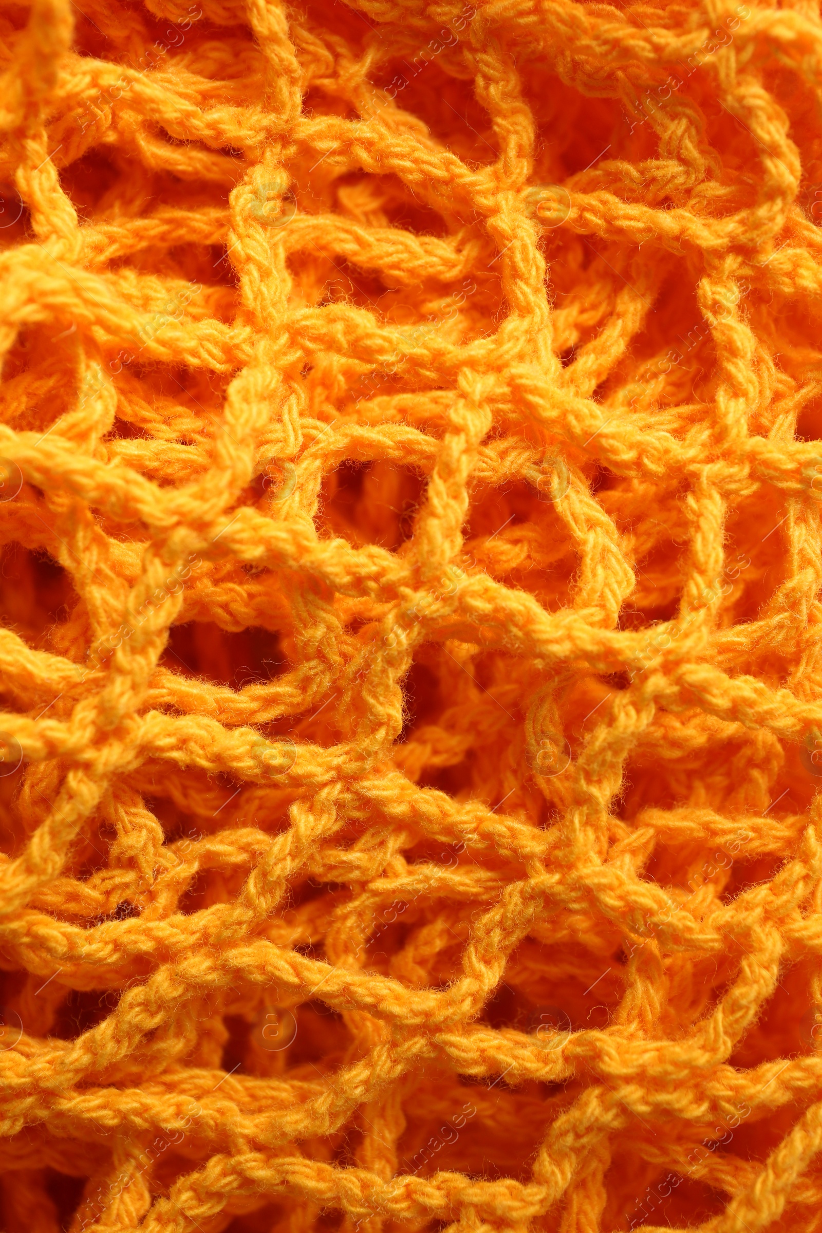 Photo of Orange knitted net as background, closeup view