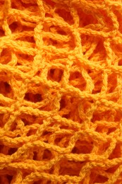 Photo of Orange knitted net as background, closeup view