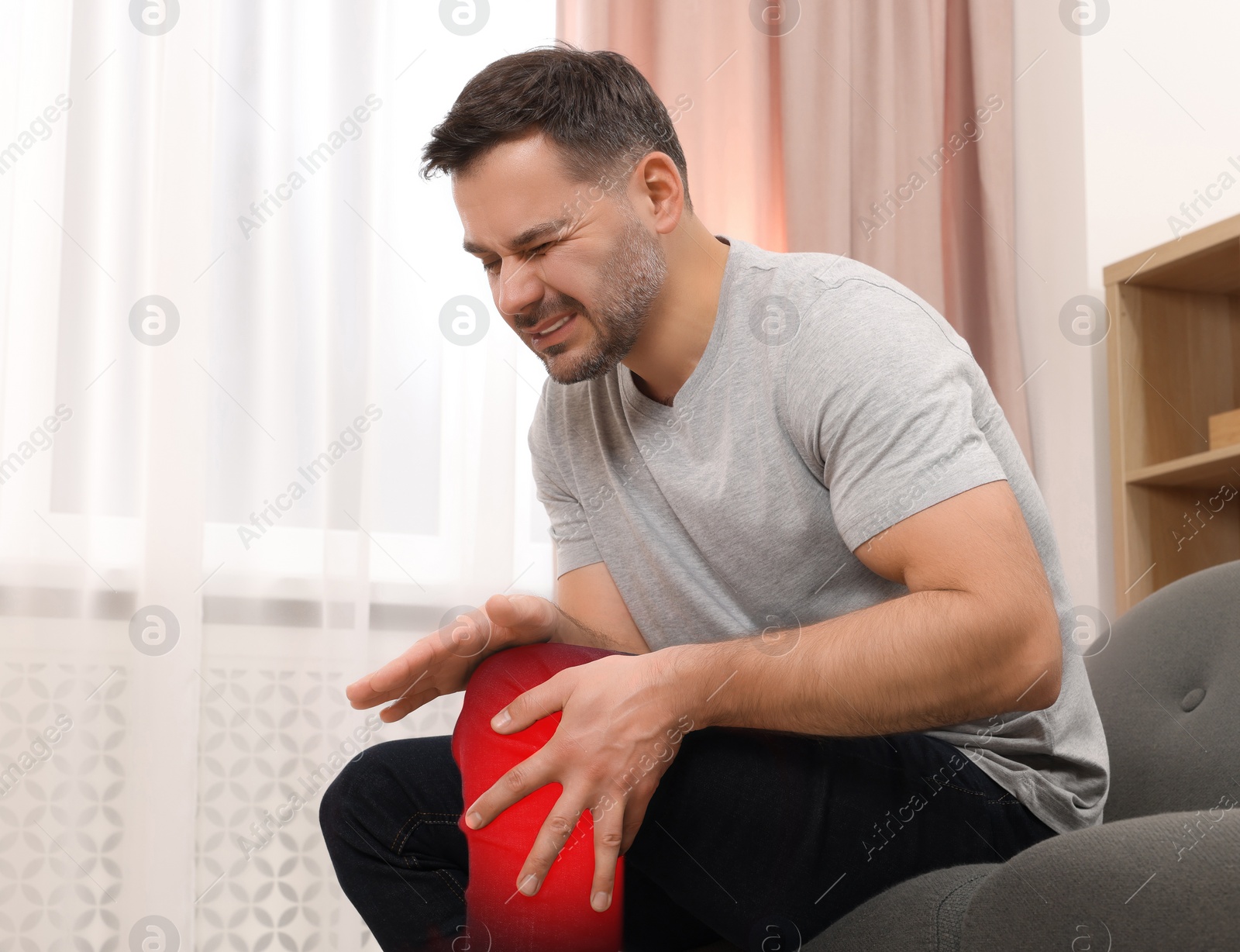 Image of Man suffering from rheumatism in knee at home