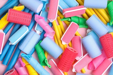 Photo of Many different hair curlers on pink background, flat lay