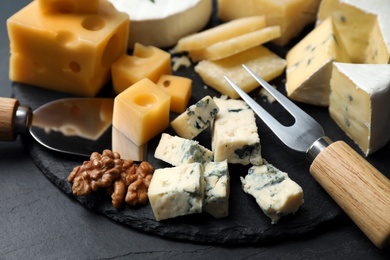 Photo of Composition with different sorts of cheese and knives on black table, closeup