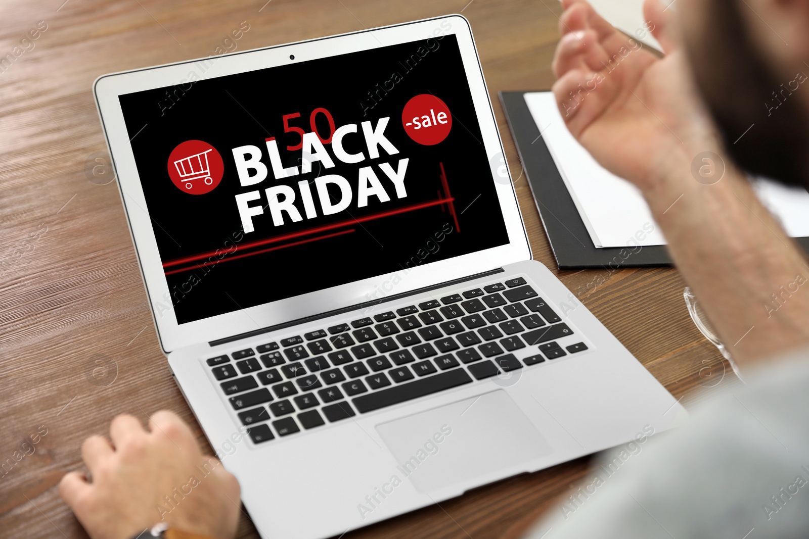 Image of Black Friday. Man shopping online using laptop at table, closeup