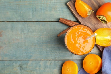 Photo of Tasty persimmon smoothie with straw and fresh fruits on light blue wooden table, flat lay. Space for text