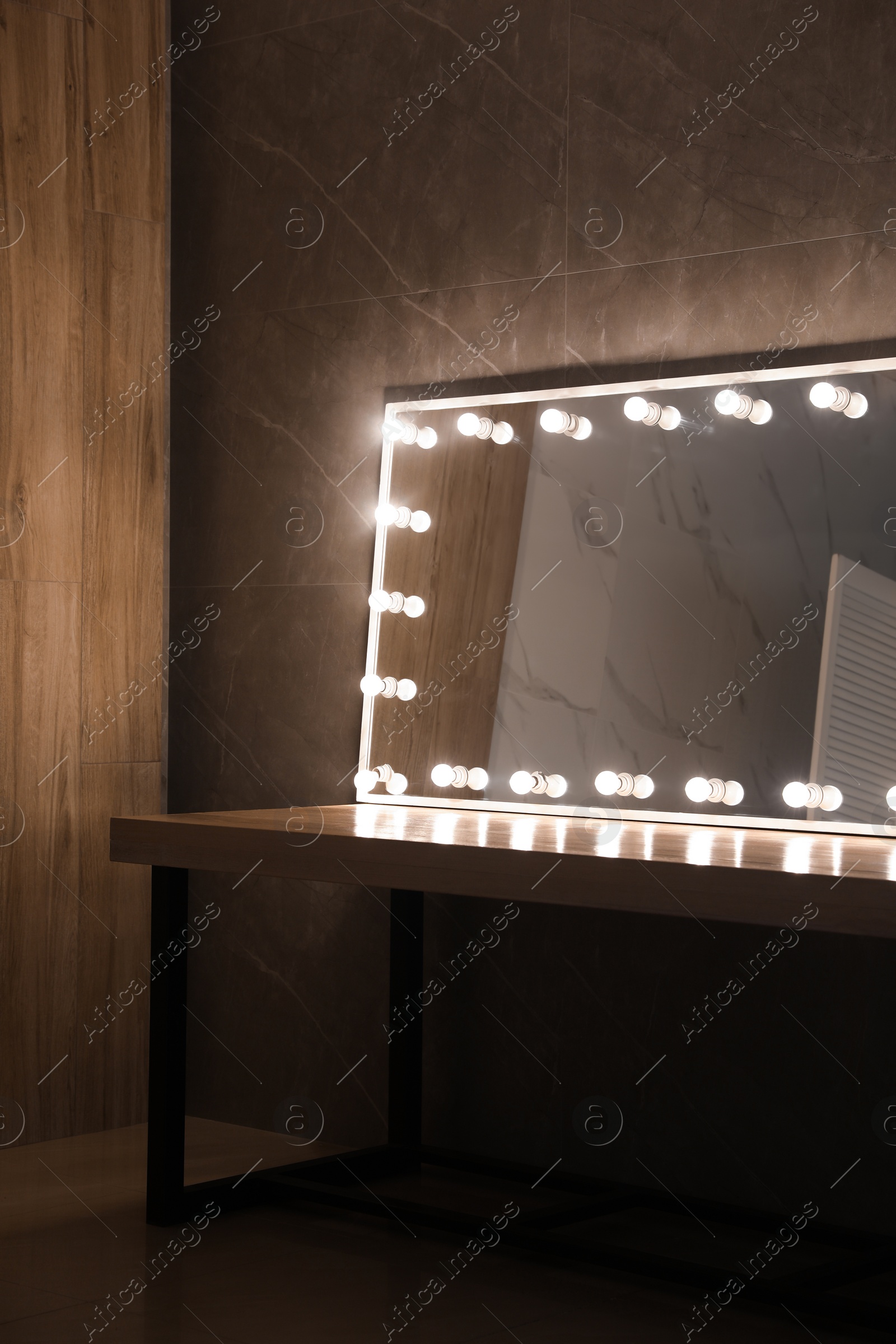 Photo of Modern mirror with light bulbs on wooden table in room