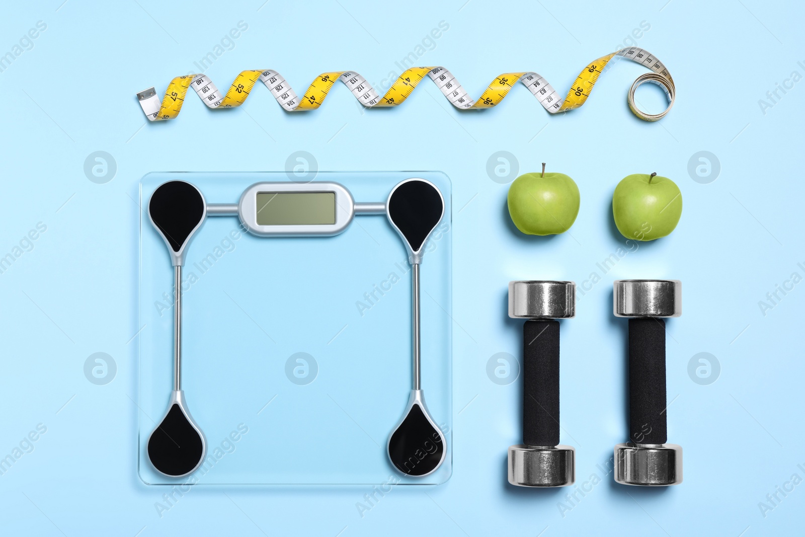 Photo of Flat lay composition with floor scales and dumbbells on light blue background. Weight loss concept
