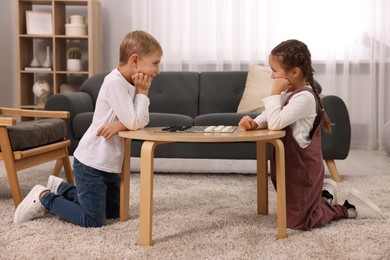 Photo of Children playing checkers at coffee table in room