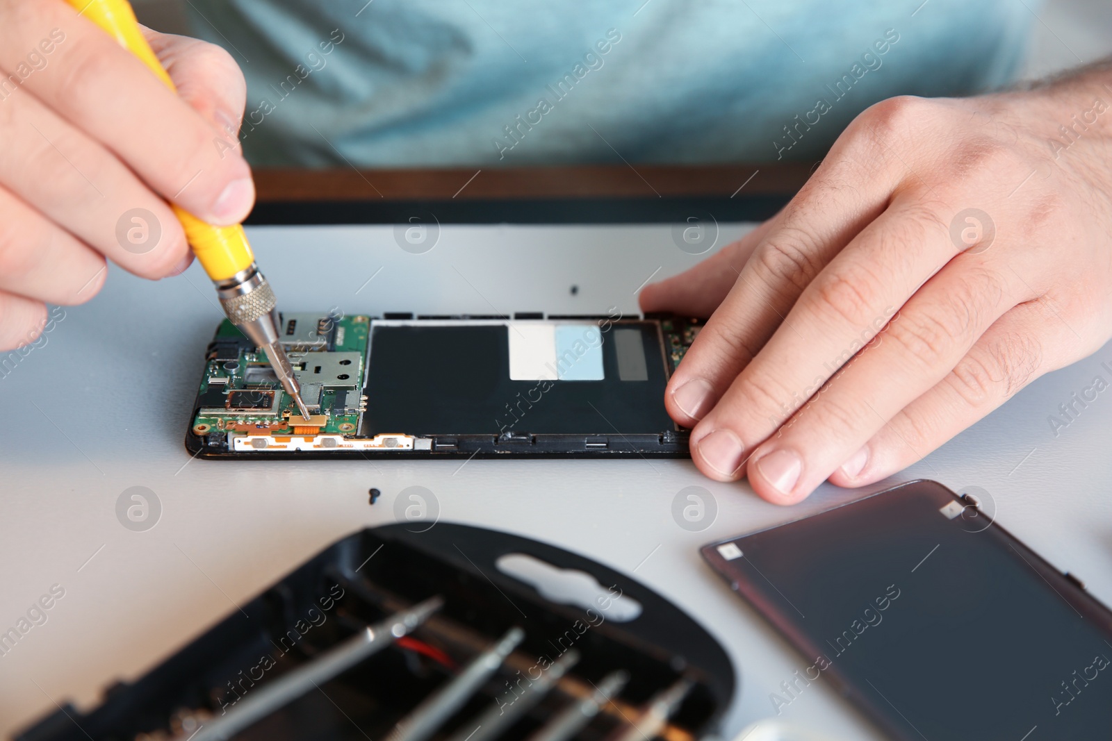 Photo of Technician repairing mobile phone at table, closeup