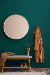 Round mirror on green wall in stylish hallway interior