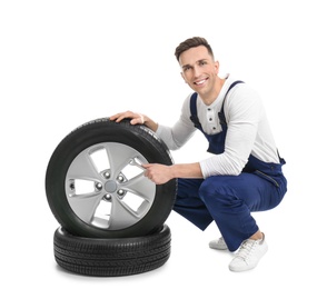 Male mechanic with car tires on white background