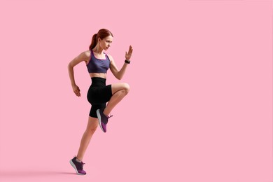 Photo of Young woman in sportswear running on pink background, space for text